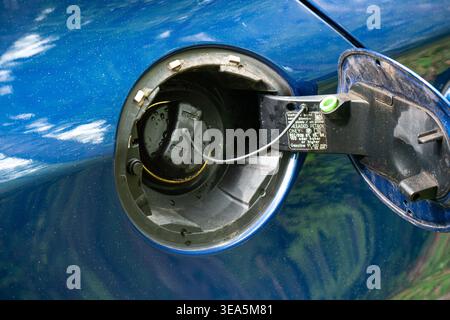 Zurigo, Svizzera, 17 aprile 2026. Chiudere lo sportello del bocchettone di rifornimento del carburante e il tappo del serbatoio di un veicolo metallico blu con specifiche del carburante visibili Foto Stock