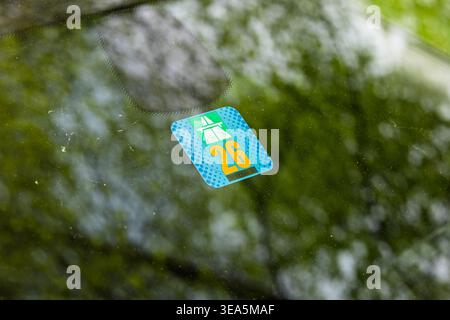 Zurigo, Svizzera, 17 aprile 2026. Primo piano di un adesivo autostradale svizzero del 2026 sul parabrezza di un'auto con riflessi verdi naturali Foto Stock