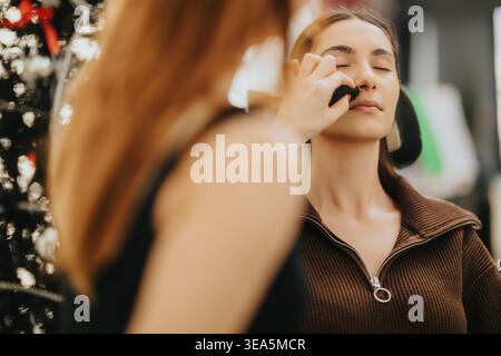 Donna che riceve una domanda di trucco da un truccatore in un centro di bellezza durante una sessione di trucco Foto Stock