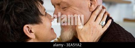 Due anziani abbracciano con gioia, condividendo un momento tenero pieno di amore e felicità al chiuso. Foto Stock