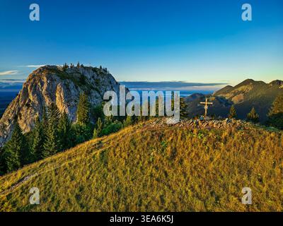 Uomo che cammina, seduto sulla cima del monte Heuberg con un muro d'acqua sullo sfondo, Alpi Chiemgau, alta Baviera, Baviera, Germania Foto Stock