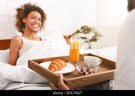 Il ragazzo porta un po' di colazione alla sua ragazza a letto Foto Stock