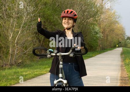 Ciclista felice che mostra un gesto con i pollici in alto durante la guida Foto Stock
