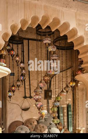 Colorate lanterne a mosaico arabo appese sotto un tradizionale arco storico a Dubai. Decorazioni ornamentali in stile mediorientale Foto Stock