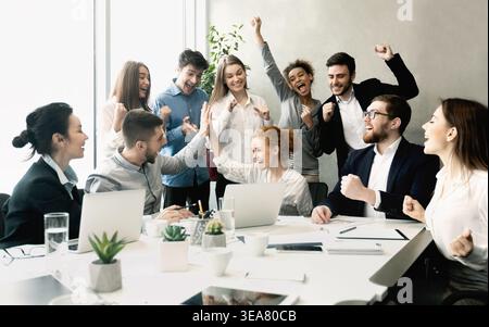 Team aziendale che celebra il successo insieme sul posto di lavoro Foto Stock