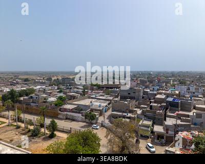 Vista aerea di edifici residenziali densamente popolati con tetti piani e stradine strette sotto un cielo azzurro a Hyderabad, Sindh, Pakistan. Foto Stock
