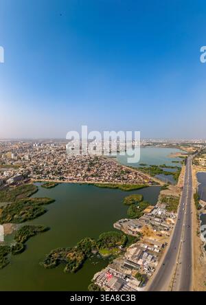 Vista aerea del paesaggio urbano e delle zone umide con una lunga autostrada sotto un cielo azzurro a Hyderabad, Sindh, Pakistan. Foto Stock