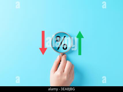 Concetto di aumento e diminuzione dei tassi di interesse. Lente di ingrandimento sul simbolo di percentuale tra le frecce rosse verso il basso e verdi verso l'alto che rappresentano l'analisi finanziaria Foto Stock
