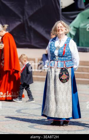 Oslo, Norvegia - 17 maggio 2025: Donna in tradizionale bunad norvegese sorridente durante la celebrazione del giorno della Costituzione, con indosso una d ricamata blu e argento Foto Stock