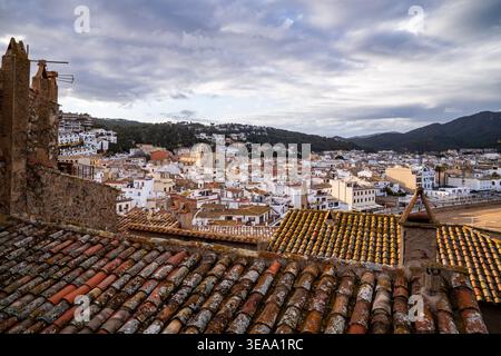 Una vista suggestiva dagli antichi tetti piastrellati di Vila Vella verso il centro di Tossa de Mar. Con la chiesa di Sant Vicenj e le colline della Costa Brava Foto Stock