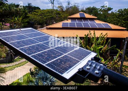 Pannelli solari fotovoltaici installati su un tetto in tegole di argilla di una casa rustica e un lampione a energia solare in primo piano, che evidenziano la sostenibilità Foto Stock