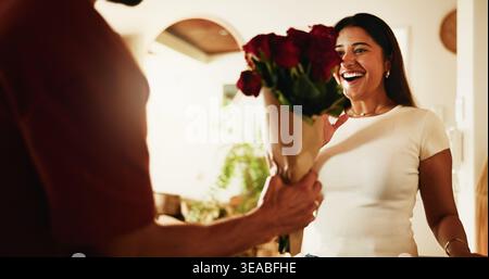 Amore, coppia e sorpresa con i fiori a casa per festeggiare l'anniversario, giorno di San Valentino o cura. Bouquet di uomini, donne e rose in casa per romantici Foto Stock