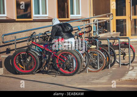 Fila di biciclette parcheggiate vicino all'ingresso dell'edificio che rappresenta il trasporto sostenibile, la mobilità urbana e uno stile di vita sano. Foto Stock