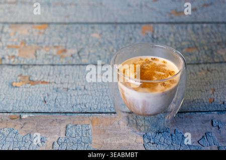 Vista dall'alto del caffè sporco in vetro a doppia parete su un tavolo in legno blu rustico. Routine Hygge mattutina con spazio di copia per il design. Foto Stock