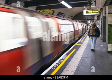 Il confuso treno della metropolitana di Londra passa davanti a un passeggero della piattaforma. Londra, Regno Unito, 3 marzo 2024 Foto Stock