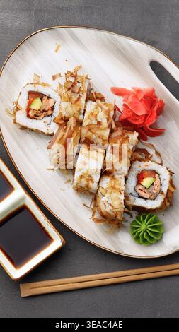 Panini di sushi serviti su un piatto con condimenti e salse in un ambiente da pranzo Foto Stock