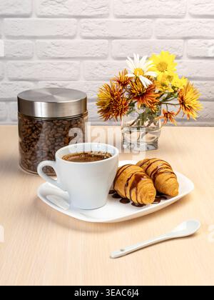 Tazza di caffè nero e croissant freschi sul piatto in porcellana bianca. Foto Stock