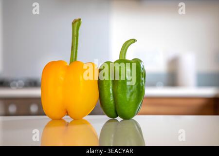 Un peperone giallo e verde su un piano di lavoro in cucina. Foto Stock