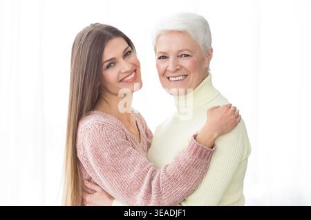 Madre e figlia senior che abbracciano e guardano la macchina fotografica Foto Stock