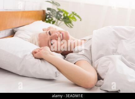 Donna matura coricato nel suo letto a casa Foto Stock