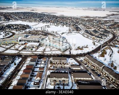 Coperte di neve per le case e le strade dell'Hampton Village. La vista aerea mostra edifici raggruppati e strade tortuose. La neve fresca copre tetti e spazi aperti Foto Stock