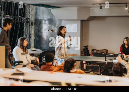 Gli studenti giocano a ping-pong in uno spazio ricreativo informale e inclusivo presso un college o un centro comunitario Foto Stock