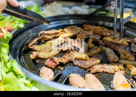 Grigliata coreana alla griglia con pancetta di maiale marinata e salsicce, lattuga fresca e contorni Foto Stock