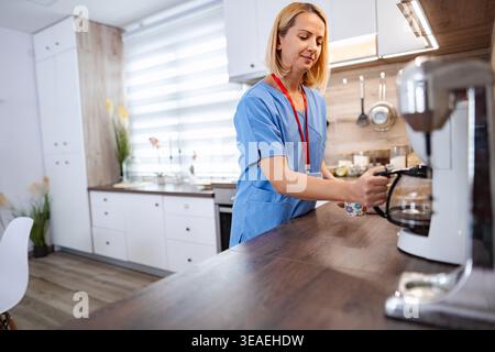 Infermiera che prepara il caffè in cucina durante una pausa Foto Stock