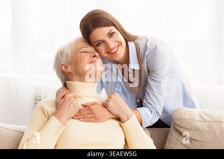 Momenti caldi condivisi tra una donna anziana e una giovane donna in un accogliente ambiente interno Foto Stock