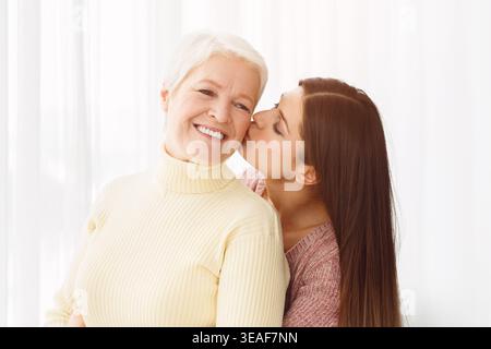 Giovane figlia di baciare senior madre nella guancia Foto Stock