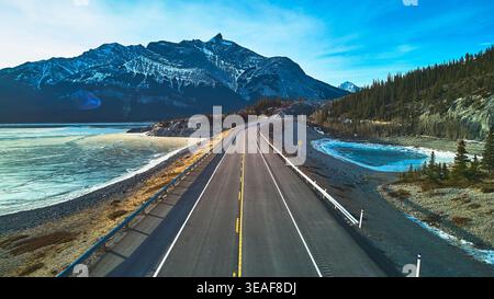 Aerial Frozen Lake Mountain Road e Pine Forest con paesaggio invernale Foto Stock