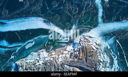 Le fessure di ghiaccio del lago ghiacciato dall'alto e il panorama invernale della costa rocciosa Foto Stock