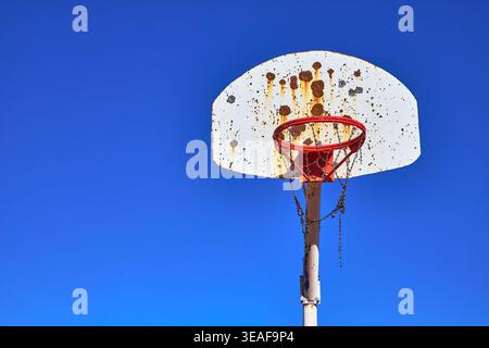 Vecchio canestro da basket all'aperto contro il cielo blu con Rust e Chain Net Foto Stock
