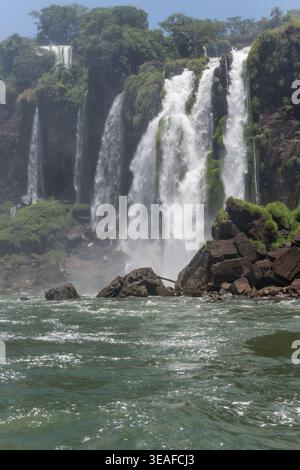 Paesaggio con l'acqua dell'Iguazú inferiore e il salto Mendez nel parco naturale, girato dal basso con la luce brillante dell'estate alle cascate dell'Iguazu, Misiones, Argentina Foto Stock