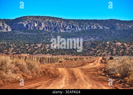 Dirt Road e Wooden Fence che conducono alle Desert Cliffs a Mount Trumbull, Arizona Foto Stock
