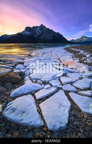 Alba invernale sul lago ghiacciato con Broken Ice e Majestic Mountain Peaks Foto Stock