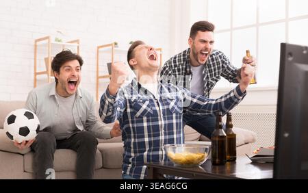 I vincitori. Amici eccitato guardando la partita di calcio a casa Foto Stock