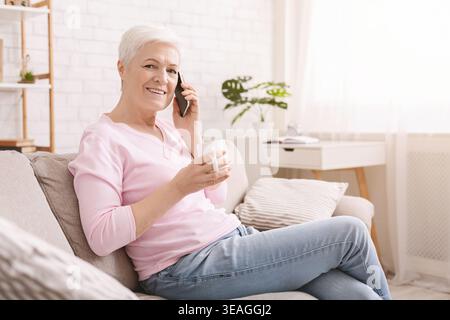 Una donna anziana ama conversare al telefono mentre è seduto comodamente a casa Foto Stock