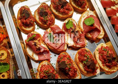 Fette di pane tostato condite con tartare di manzo macinato fresco e guarnite con microverdure. Foto Stock