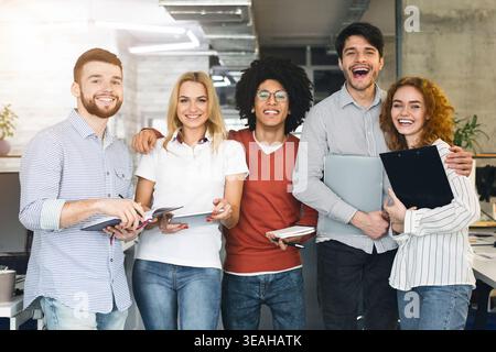 Gruppo di giovani professionisti che sorridono insieme in un moderno ambiente d'ufficio durante la giornata Foto Stock