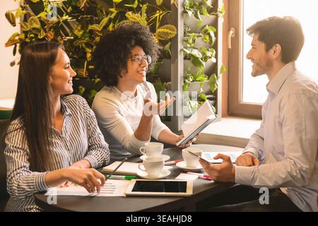Giovani multietnica team aziendali di condividere idee in cafe Foto Stock