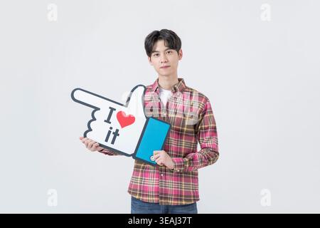 Un giovane tiene un dito di schiuma grande con le parole "lo amo" e un simbolo del cuore. Foto Stock