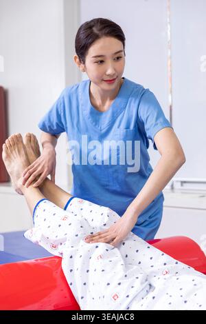 Una fisioterapista femminile assiste un paziente con esercizi di stretching in una clinica di riabilitazione. Foto Stock