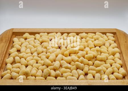 Pasta fresca di gnocchi di patate italiane crude su un vassoio di legno isolato su sfondo bianco. Foto Stock