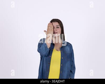 Donna che copre il suo occhio con una mano in studio Foto Stock