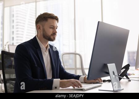 Uomo d'affari che lavora su un computer desktop in un ufficio moderno Foto Stock