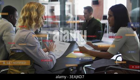 Revisione del team che indossa documenti aziendali e notebook durante una riunione, mostrando sovrapposizioni dell'interfaccia utente Foto Stock