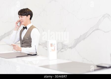 Una receptionist sta rispondendo a una telefonata alla reception. Foto Stock