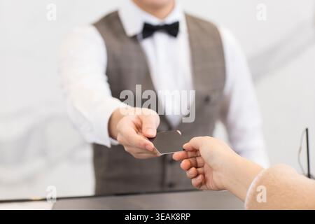 Un cliente consegna una carta di credito all'addetto alla reception dell'hotel al banco del check-in. Foto Stock