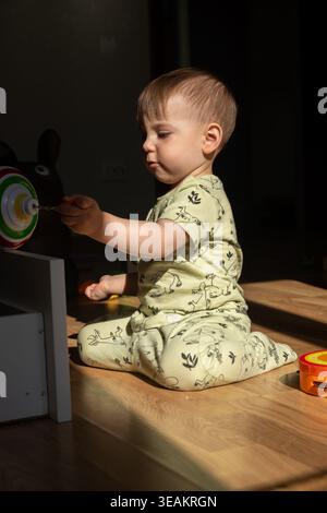 Il bambino gioca con il giocattolo in una stanza illuminata dal sole Foto Stock